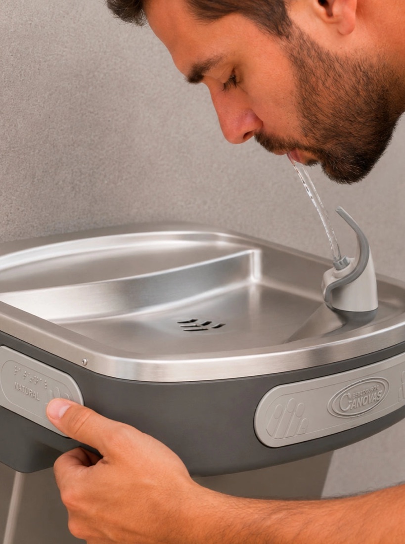 Persona tomando agua de un bebedero Cánovas de acero inoxidable